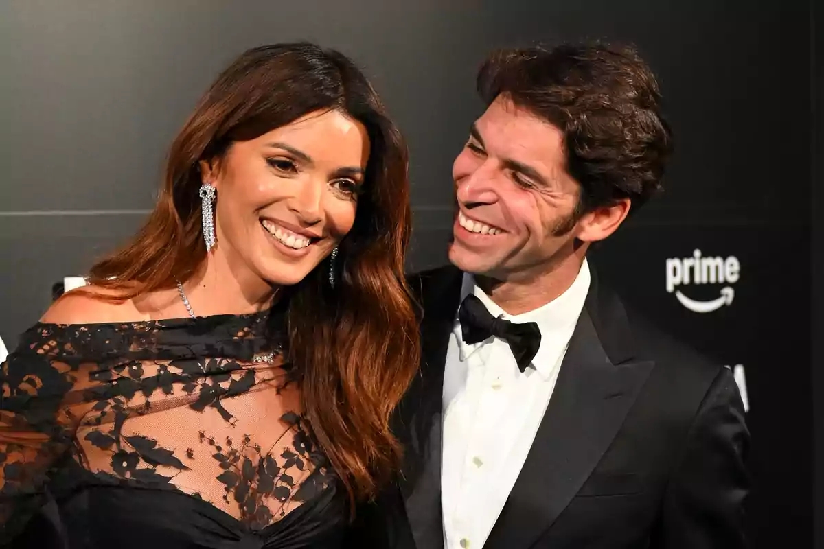 María Cerqueira y Cayetano Rivera elegantemente vestida sonríe en un evento con fondo negro y logotipos de Prime. María Cerqueira y Cayetano Rivera elegantemente vestida sonríe en un evento con fondo negro y logotipos de Prime.