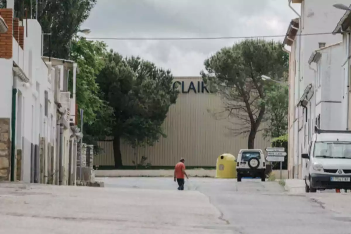 Una persona camina por una calle tranquila con edificios a los lados y un gran almacén al fondo.