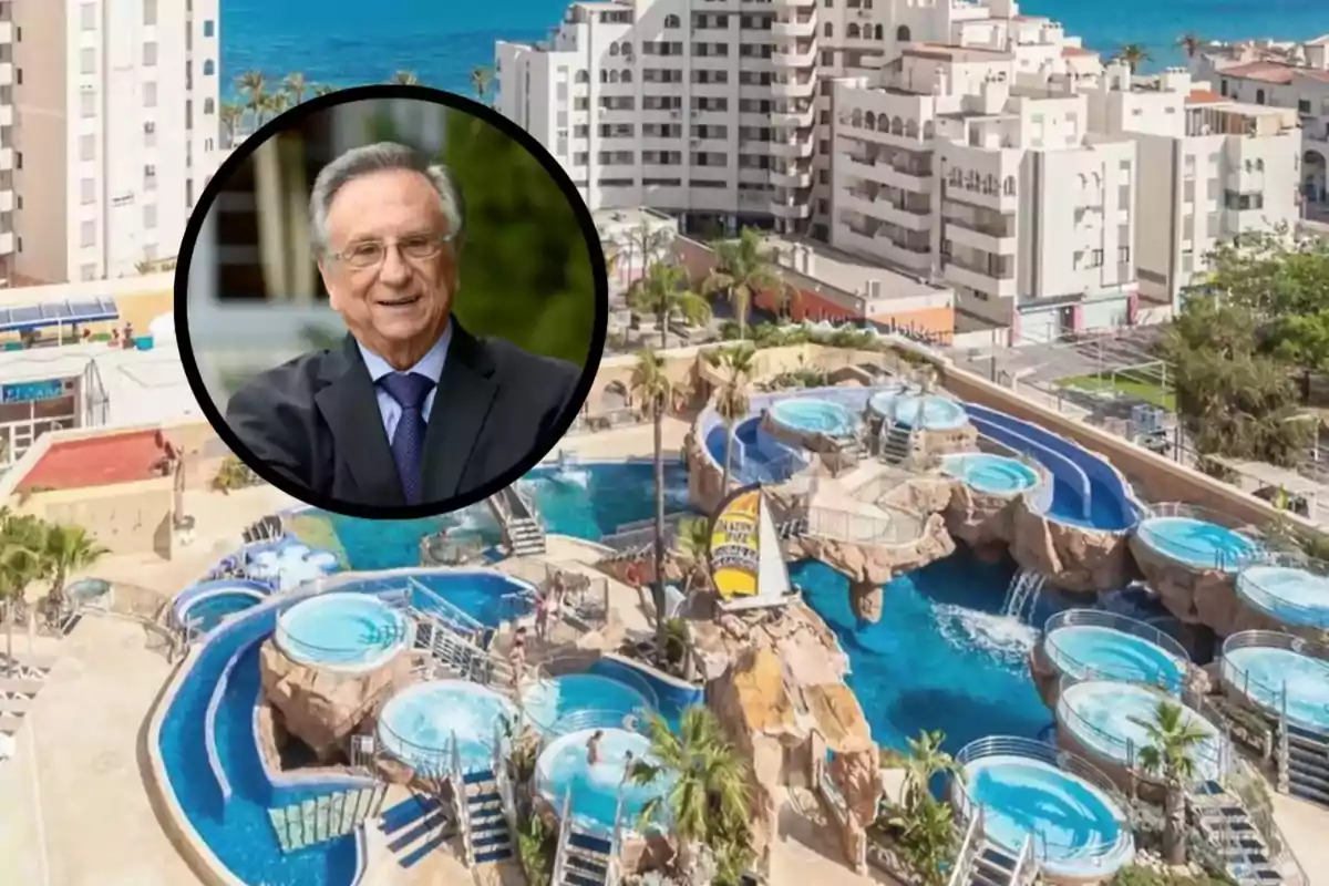 Un hombre mayor con traje sonríe en un círculo superpuesto sobre una imagen de un complejo turístico con piscinas y edificios cerca del mar.