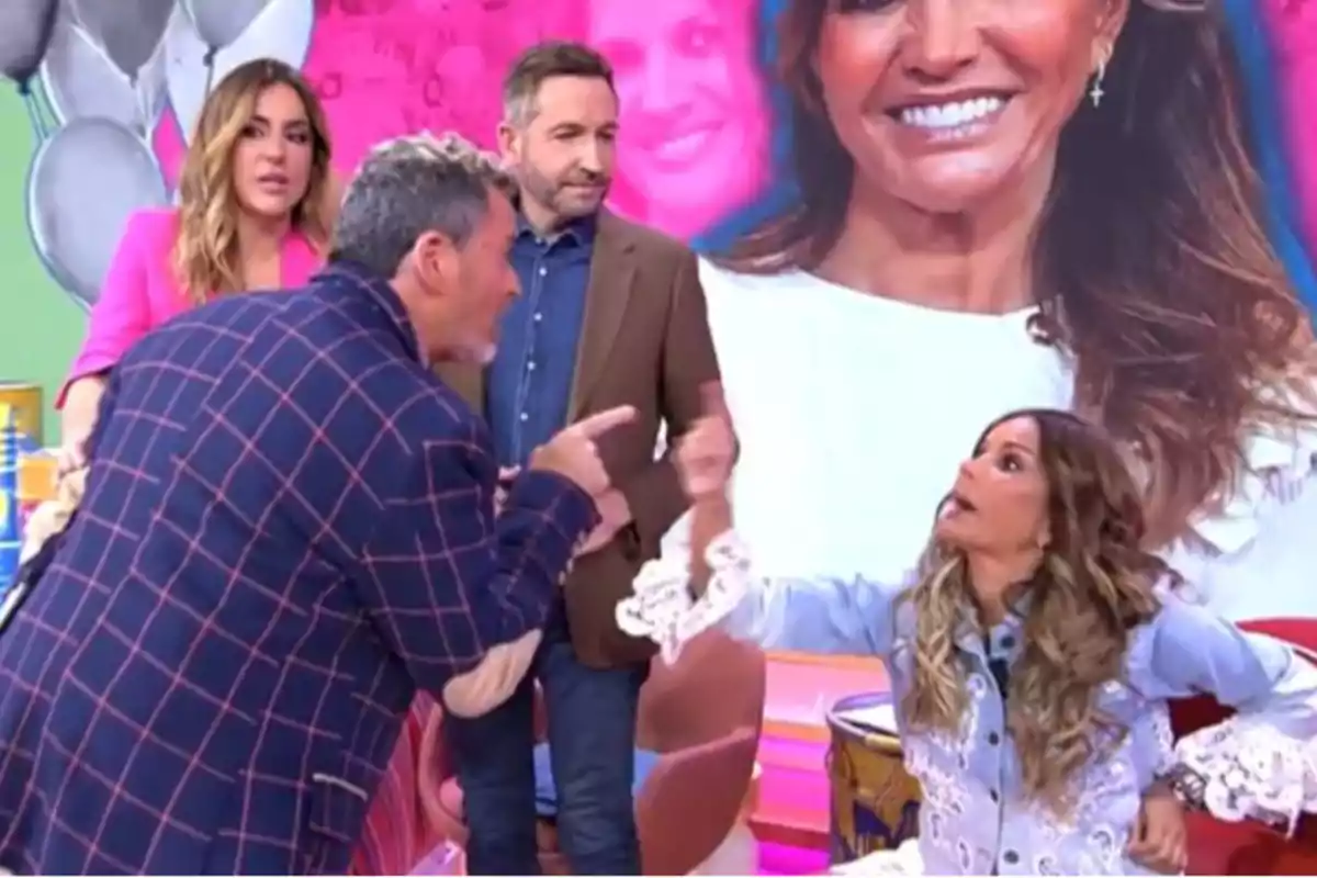 Un grupo de personas en un set de televisión parece estar discutiendo de manera acalorada mientras una gran imagen de fondo muestra a una mujer sonriendo. Un grupo de personas en un set de televisión parece estar discutiendo de manera acalorada mientras una gran imagen de fondo muestra a una mujer sonriendo.