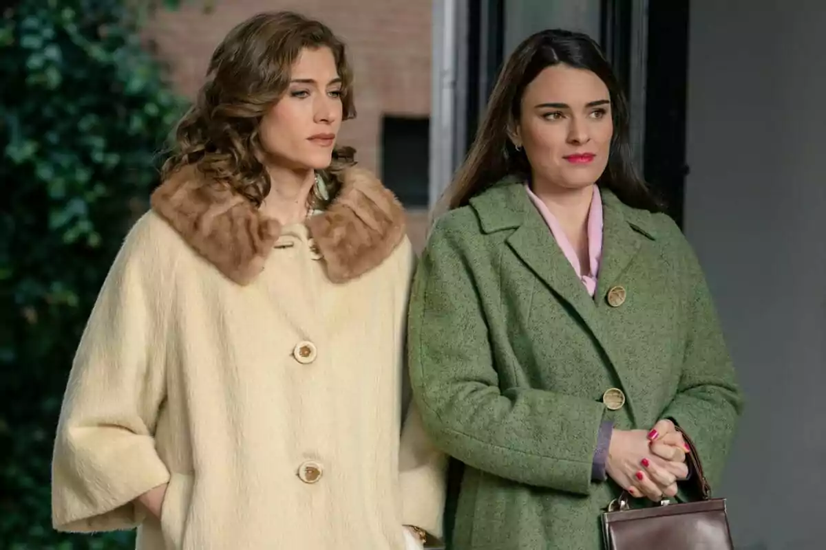 Marta Belmonte y Alba Brunet de pie, una con abrigo beige con cuello de piel y la otra con abrigo verde, ambas mirando hacia adelante en Sueños de Libertad. Marta Belmonte y Alba Brunet de pie, una con abrigo beige con cuello de piel y la otra con abrigo verde, ambas mirando hacia adelante en Sueños de Libertad.