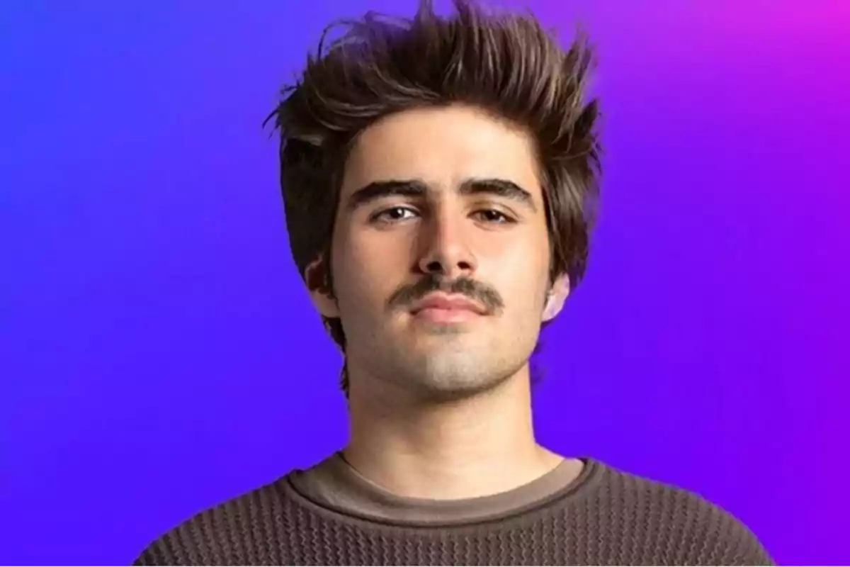 Un hombre joven con bigote y cabello oscuro mira hacia la cámara con un fondo degradado de azul a morado.