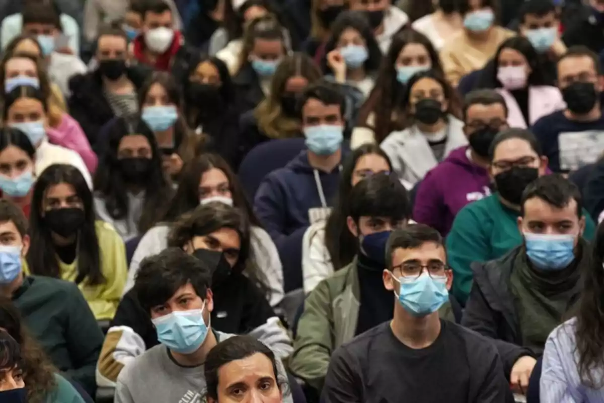 Un grupo de personas sentadas en un auditorio, la mayoría usando mascarillas.