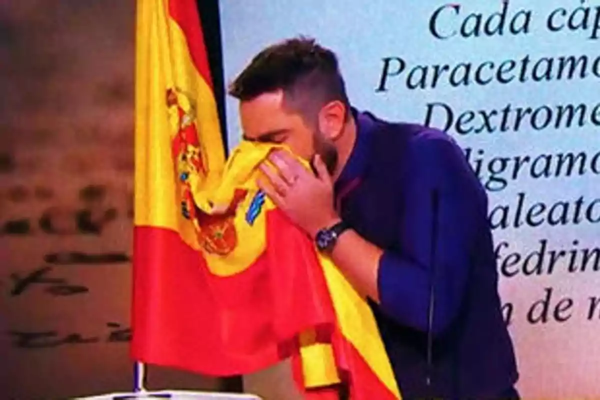 Un hombre besa una bandera de España en un entorno que parece ser un estudio de televisión.