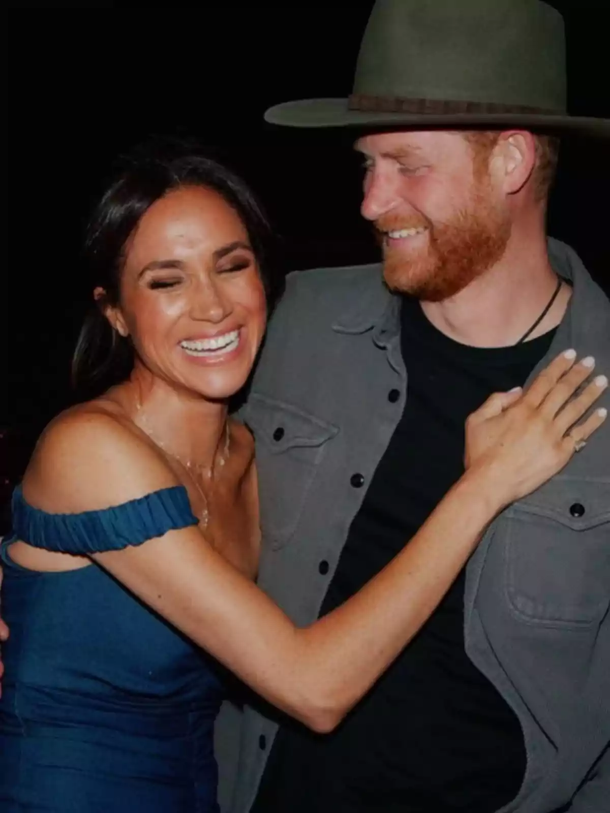Una pareja sonriente se abraza, la mujer lleva un vestido azul y el hombre un sombrero verde. Una pareja sonriente se abraza, la mujer lleva un vestido azul y el hombre un sombrero verde.