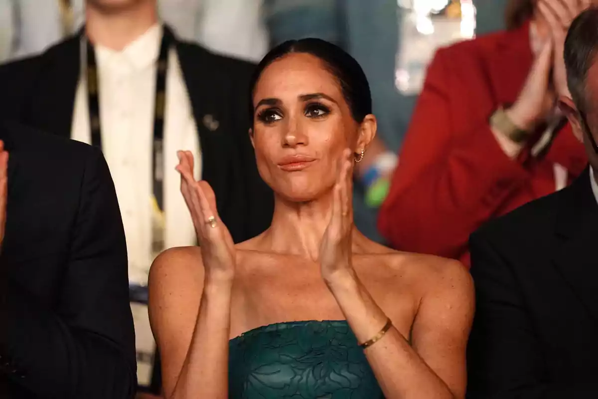 Meghan Markle aplaudiendo en un evento, rodeada de otras personas. Meghan Markle aplaudiendo en un evento, rodeada de otras personas.