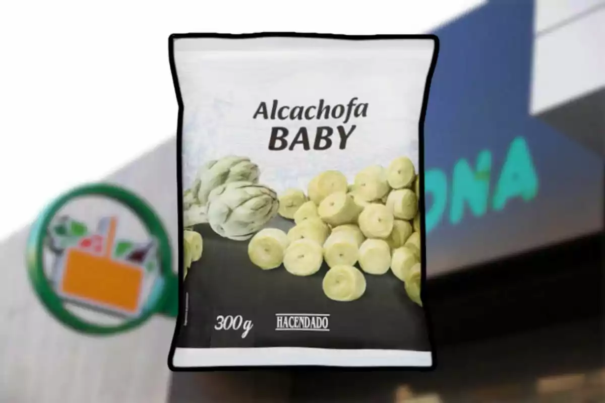 Bolsa de alcachofa baby congelada de la marca Hacendado de 300 gramos frente a una tienda Mercadona desenfocada. Bolsa de alcachofa baby congelada de la marca Hacendado de 300 gramos frente a una tienda Mercadona desenfocada.