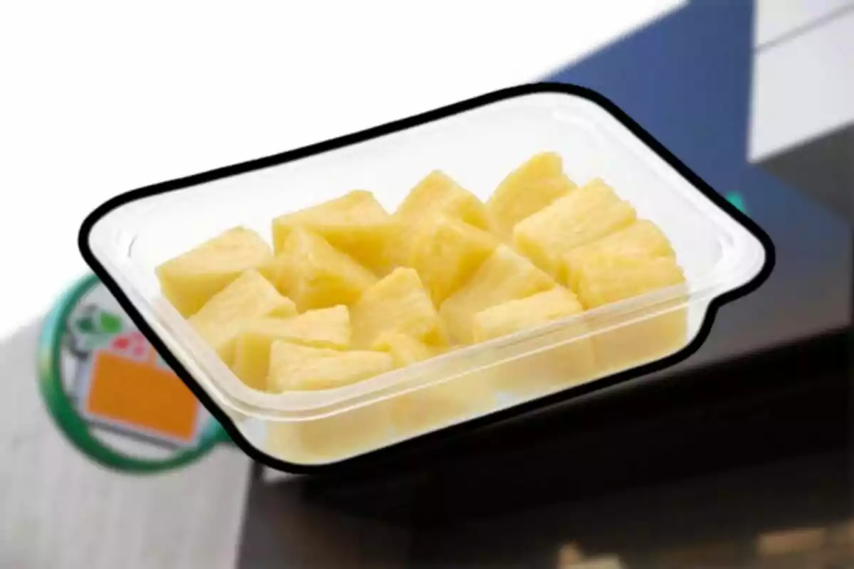 Envase de plástico transparente con trozos de piña amarilla sobre un fondo borroso Envase de plástico transparente con trozos de piña amarilla sobre un fondo borroso