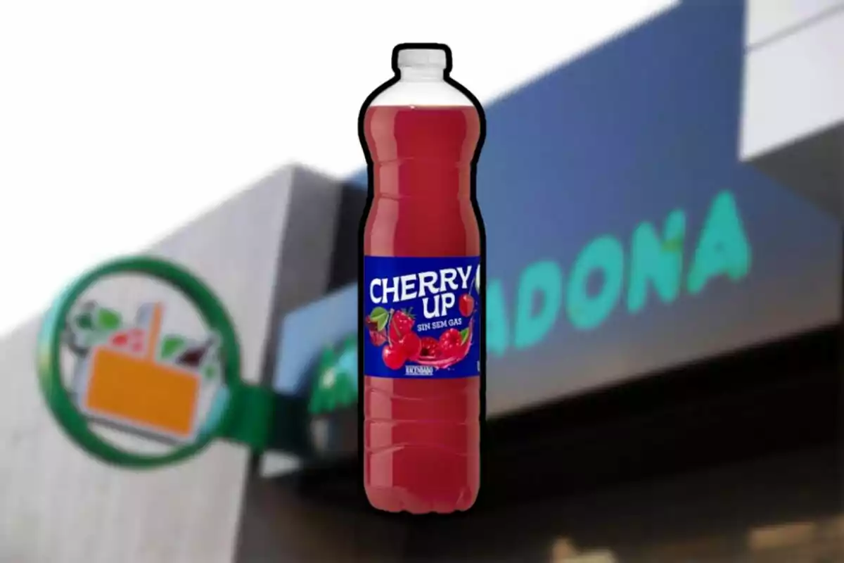 Una botella de bebida de cereza sin gas con una etiqueta azul se encuentra frente a un fondo borroso de un supermercado. Una botella de bebida de cereza sin gas con una etiqueta azul se encuentra frente a un fondo borroso de un supermercado.