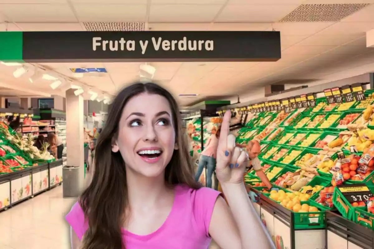 Mujer sonriendo y señalando hacia arriba en la sección de frutas y verduras de un supermercado.