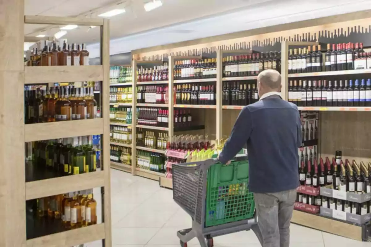 Hombre empujando un carrito de compras en la sección de vinos y licores de un supermercado Hombre empujando un carrito de compras en la sección de vinos y licores de un supermercado