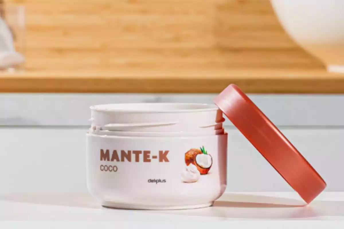 Un envase de crema de coco con tapa roja está abierto sobre una superficie blanca, mostrando su contenido cremoso. Un envase de crema de coco con tapa roja está abierto sobre una superficie blanca, mostrando su contenido cremoso.