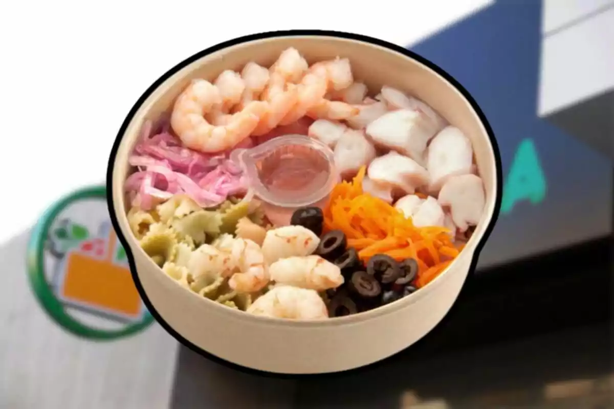 Ensalada de mariscos con camarones, pulpo, pasta de colores, zanahoria rallada, aceitunas negras, cebolla morada y aderezo en un recipiente redondo Ensalada de mariscos con camarones, pulpo, pasta de colores, zanahoria rallada, aceitunas negras, cebolla morada y aderezo en un recipiente redondo