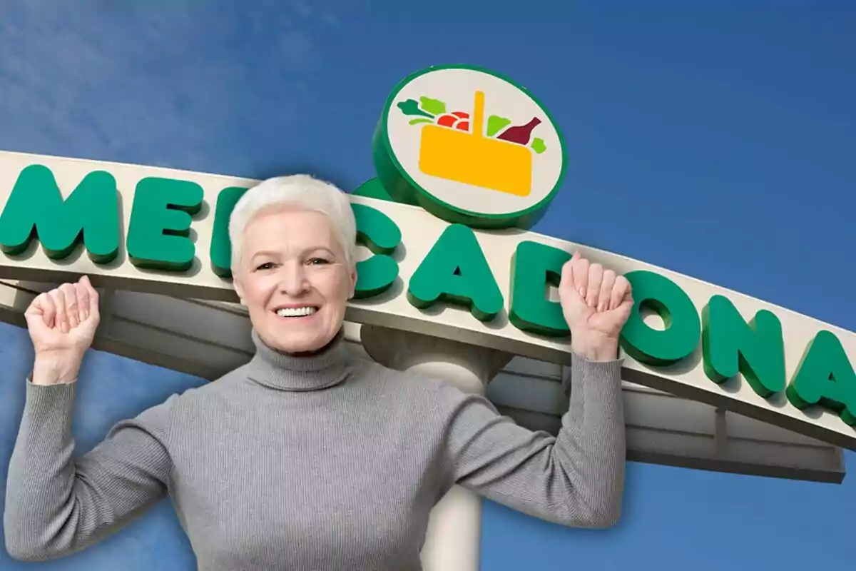 Una persona sonriente con un jersey gris levanta los brazos frente a un cartel de supermercado.