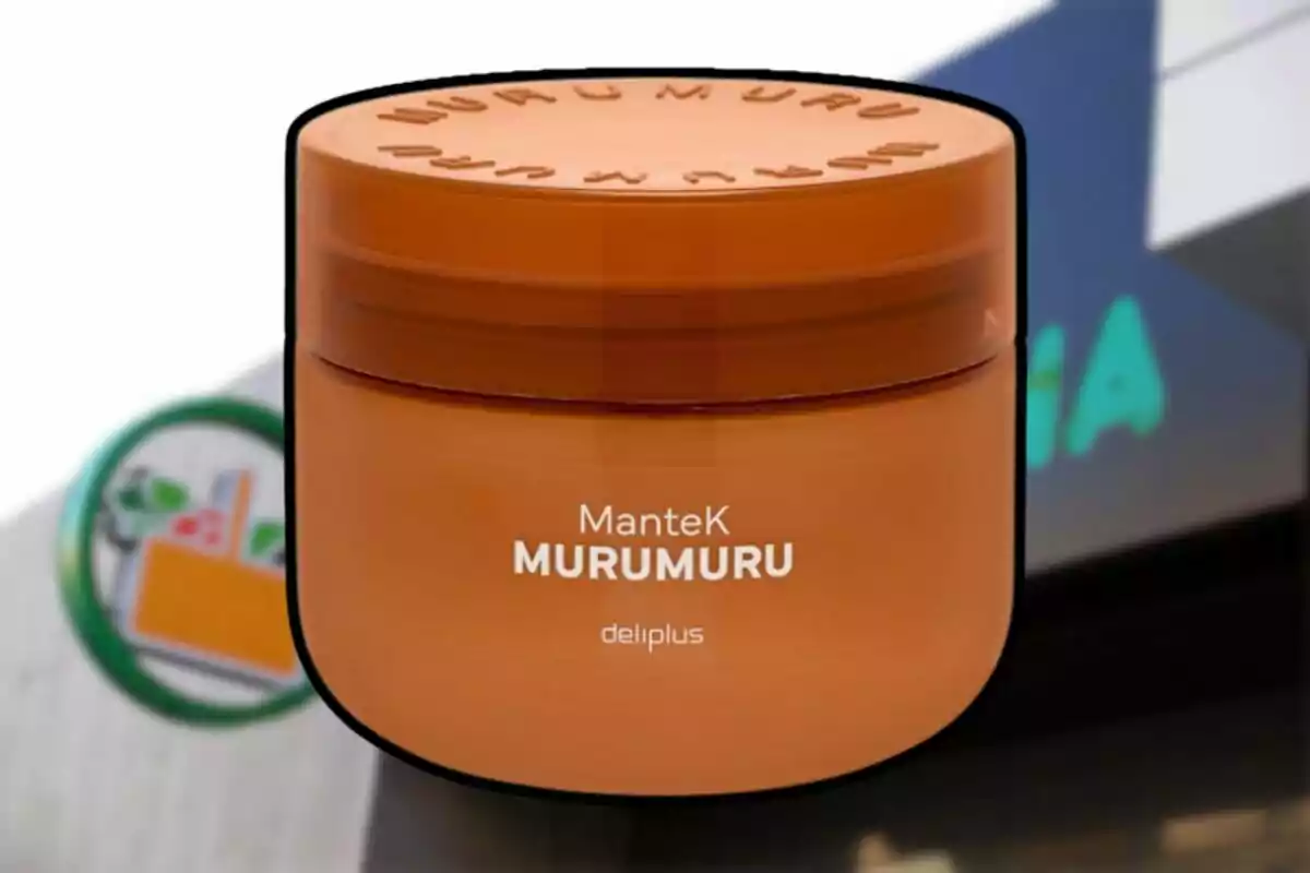 Envase redondo de color naranja de manteca Murumuru de la marca Deliplus frente a un cartel de supermercado desenfocado. Envase redondo de color naranja de manteca Murumuru de la marca Deliplus frente a un cartel de supermercado desenfocado.