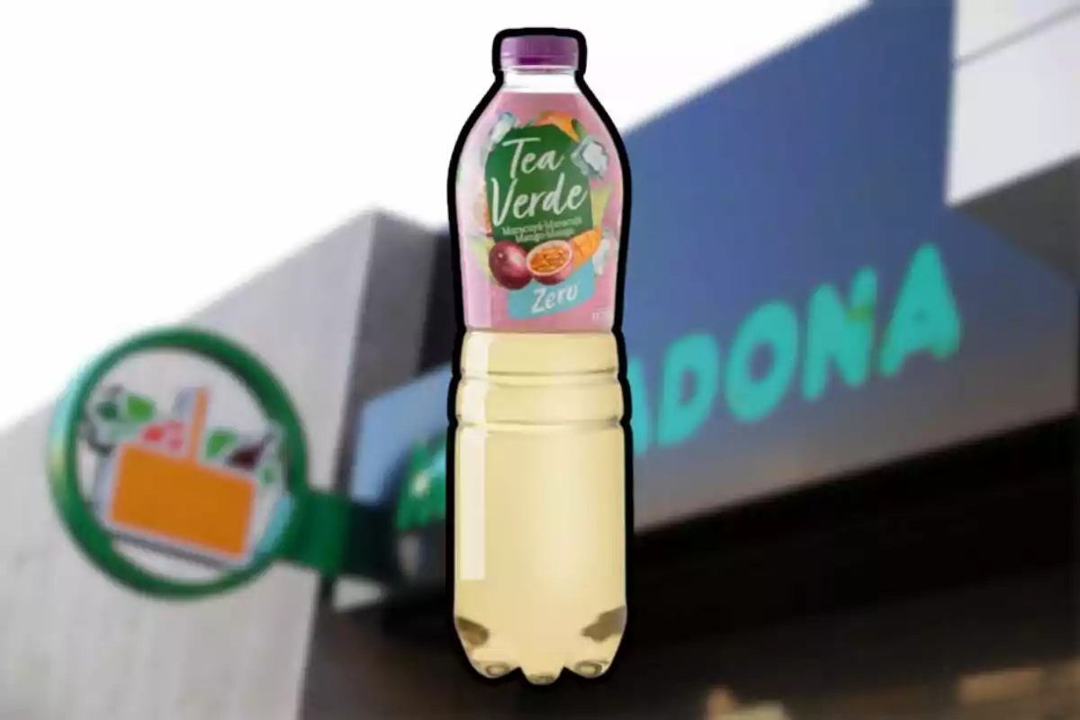 Botella de té verde sabor maracuyá y mango con etiqueta rosa frente a una tienda Mercadona desenfocada Botella de té verde sabor maracuyá y mango con etiqueta rosa frente a una tienda Mercadona desenfocada