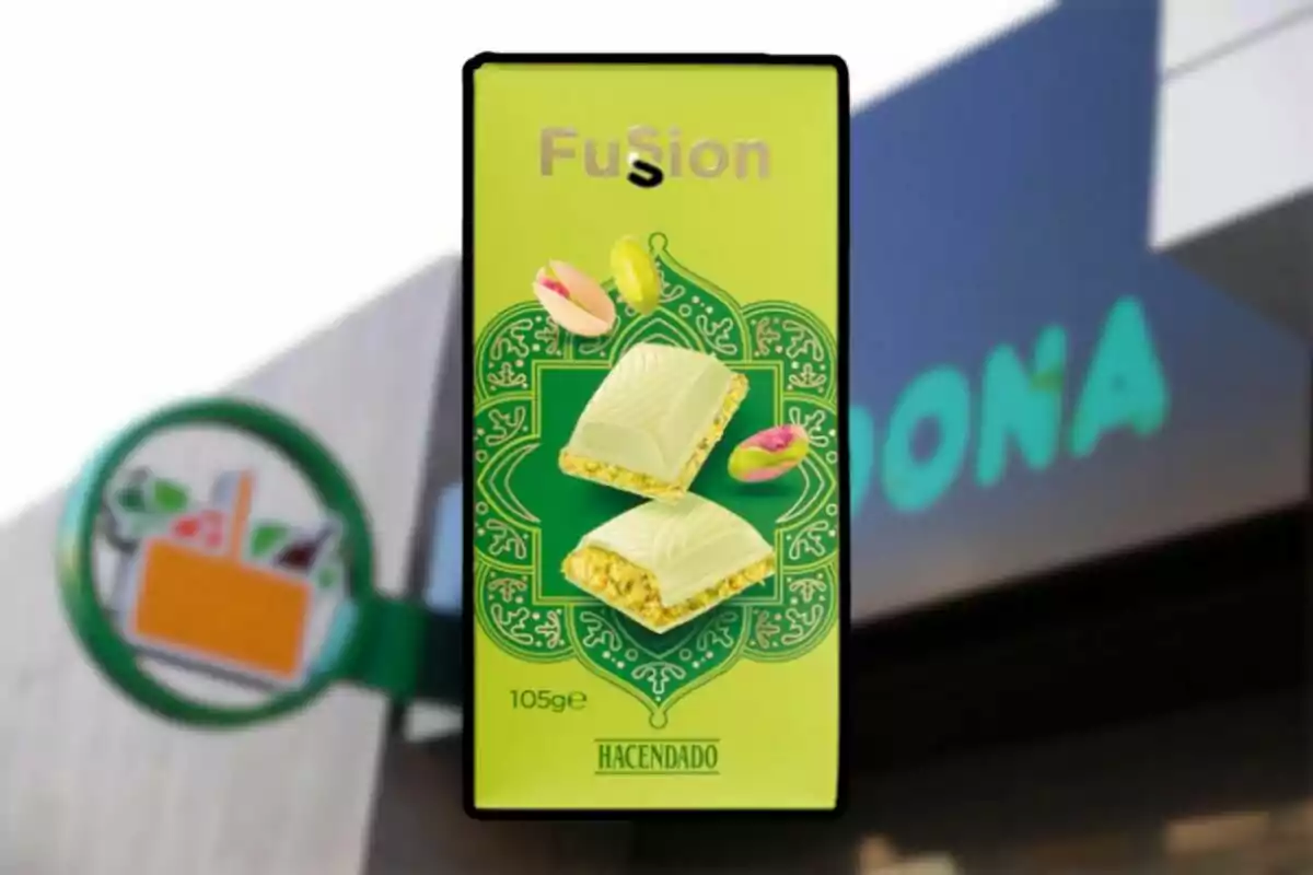 Caja de chocolate blanco con pistacho de la marca Hacendado sobre un fondo que muestra parte de un letrero de supermercado. Caja de chocolate blanco con pistacho de la marca Hacendado sobre un fondo que muestra parte de un letrero de supermercado.