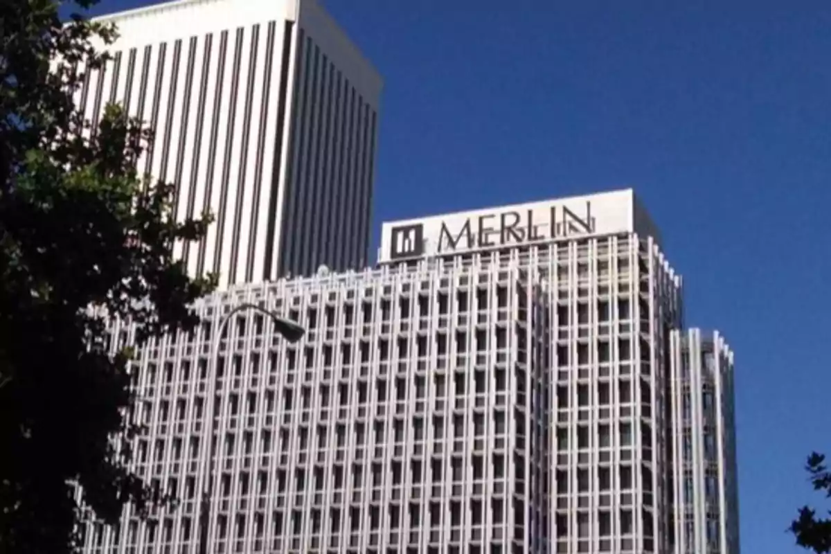 Edificio moderno con fachada de rejilla y letrero de Merlin en la parte superior bajo un cielo azul Edificio moderno con fachada de rejilla y letrero de Merlin en la parte superior bajo un cielo azul