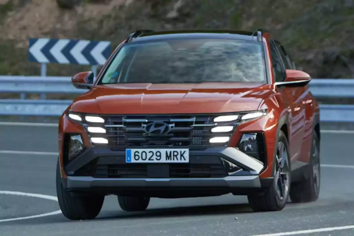 Un SUV Hyundai de color naranja circulando por una carretera con curvas.