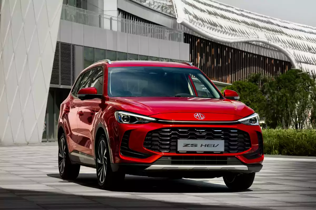 Un SUV rojo estacionado frente a un edificio moderno con diseño arquitectónico contemporáneo.