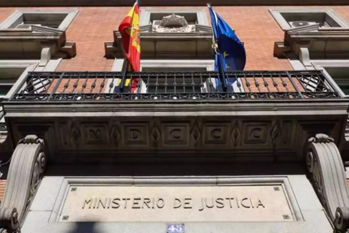 Fachada del edificio del Ministerio de Justicia con banderas de España y la Unión Europea en el balcón.