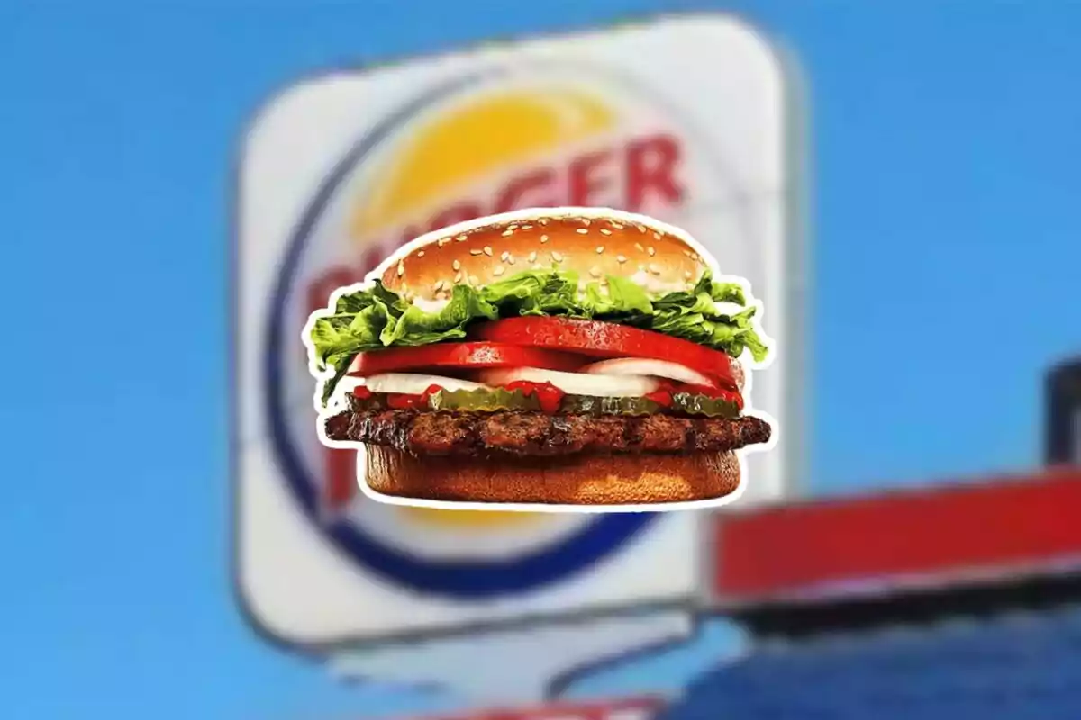 Hamburguesa con lechuga, tomate y cebolla frente a un cartel borroso de un restaurante de comida rápida. Hamburguesa con lechuga, tomate y cebolla frente a un cartel borroso de un restaurante de comida rápida.
