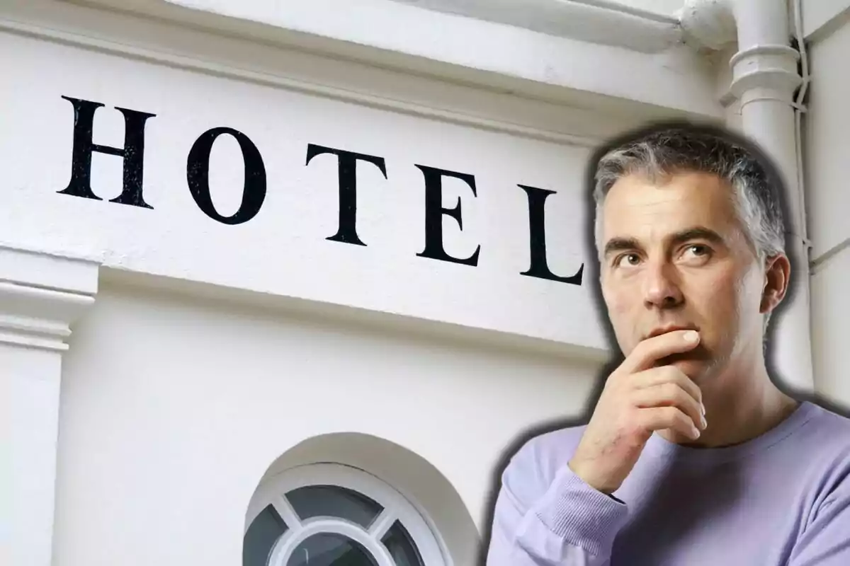 Hombre pensativo frente a un letrero de hotel.