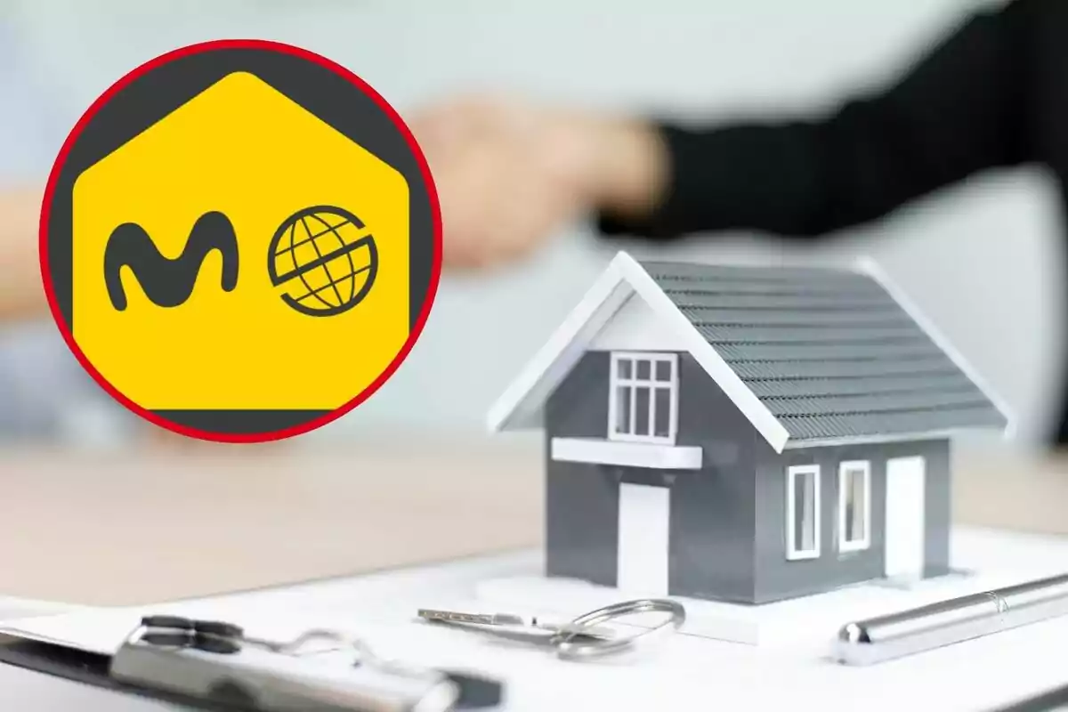 Logotipo amarillo y rojo con una casa en miniatura y un par de llaves sobre una mesa.