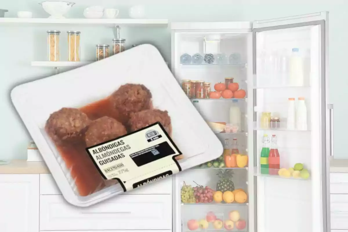 Un paquete de albóndigas guisadas de Mercadona en primer plano con un refrigerador lleno de alimentos al fondo. Un paquete de albóndigas guisadas de Mercadona en primer plano con un refrigerador lleno de alimentos al fondo.