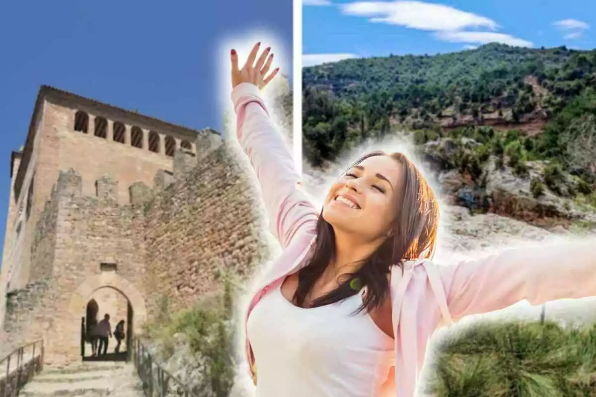 Mujer sonriente con los brazos extendidos frente a un castillo y un paisaje montañoso.