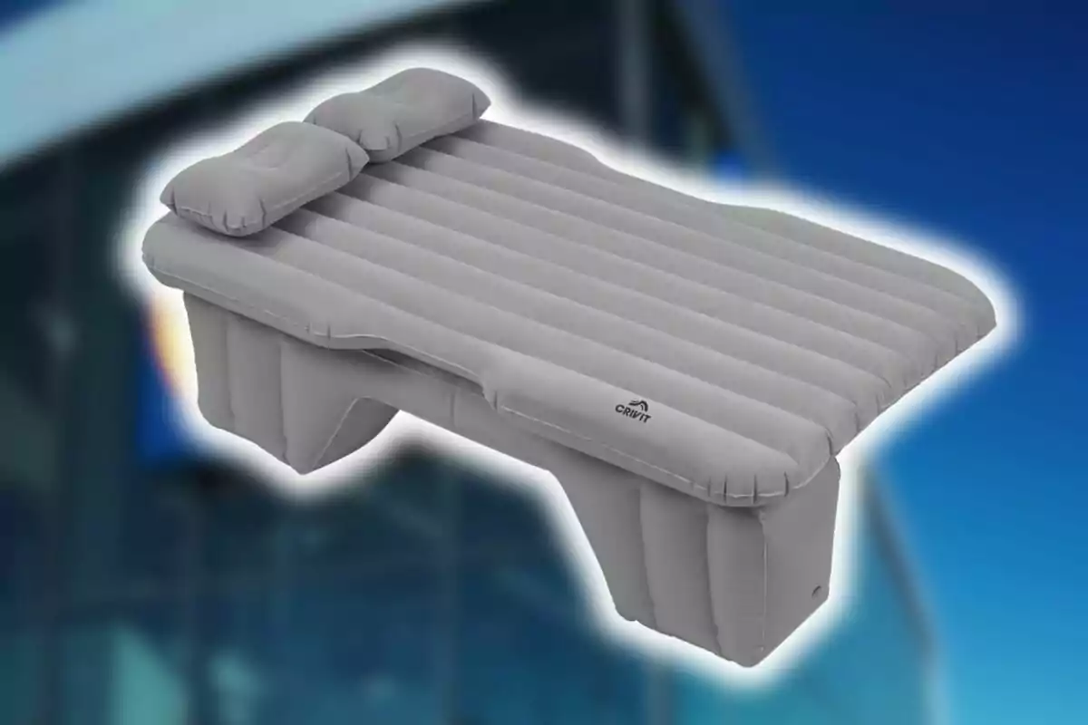 Cama inflable gris de Lidl con dos almohadas sobre un fondo azul. Cama inflable gris de Lidl con dos almohadas sobre un fondo azul.