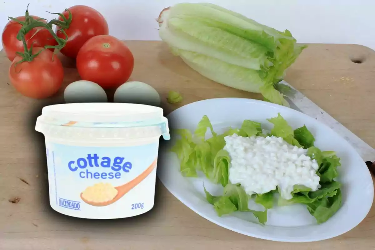 Un recipiente de queso cottage de Mercadona junto a una ensalada de lechuga, tomates y huevos sobre una tabla de cortar. Un recipiente de queso cottage de Mercadona junto a una ensalada de lechuga, tomates y huevos sobre una tabla de cortar.