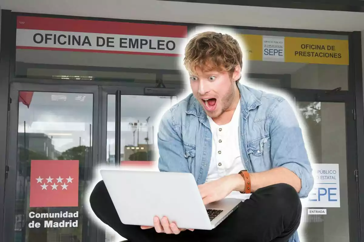 Un hombre sorprendido mirando una computadora portátil frente a una oficina de empleo en Madrid.