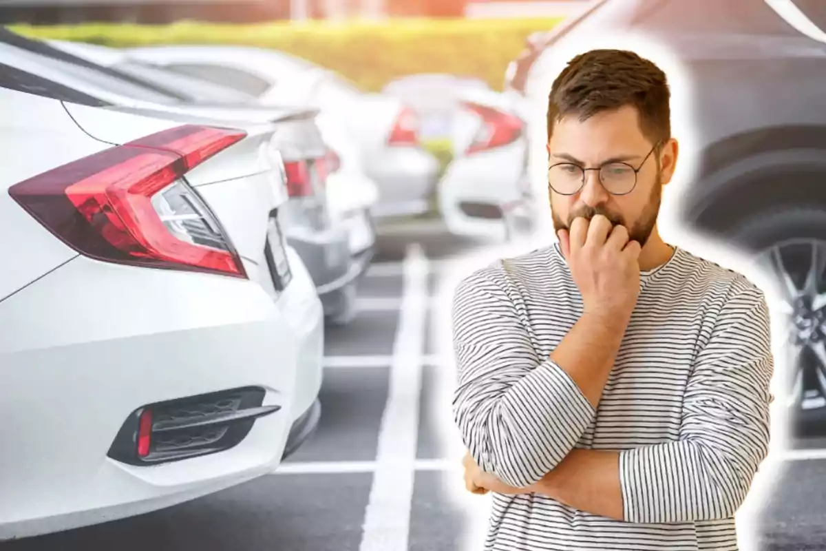 Hombre pensativo en un estacionamiento lleno de coches.