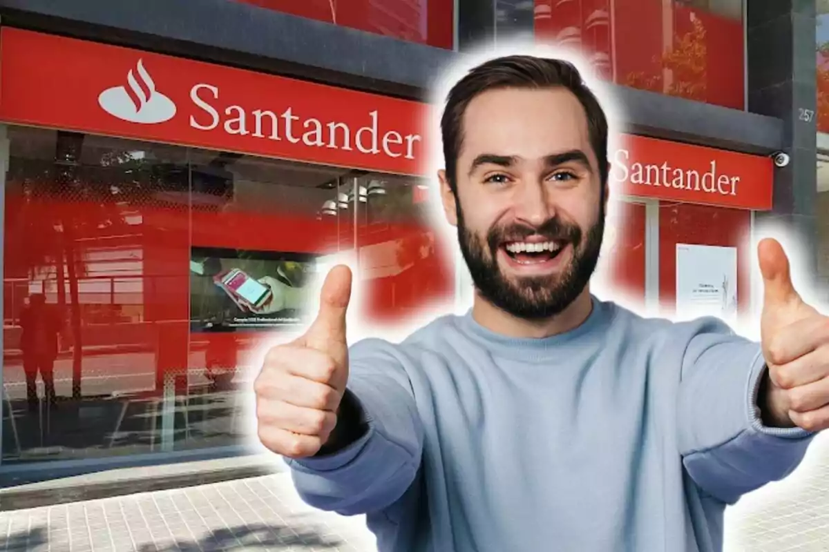 Hombre sonriente con pulgares hacia arriba frente a una sucursal del banco Santander.