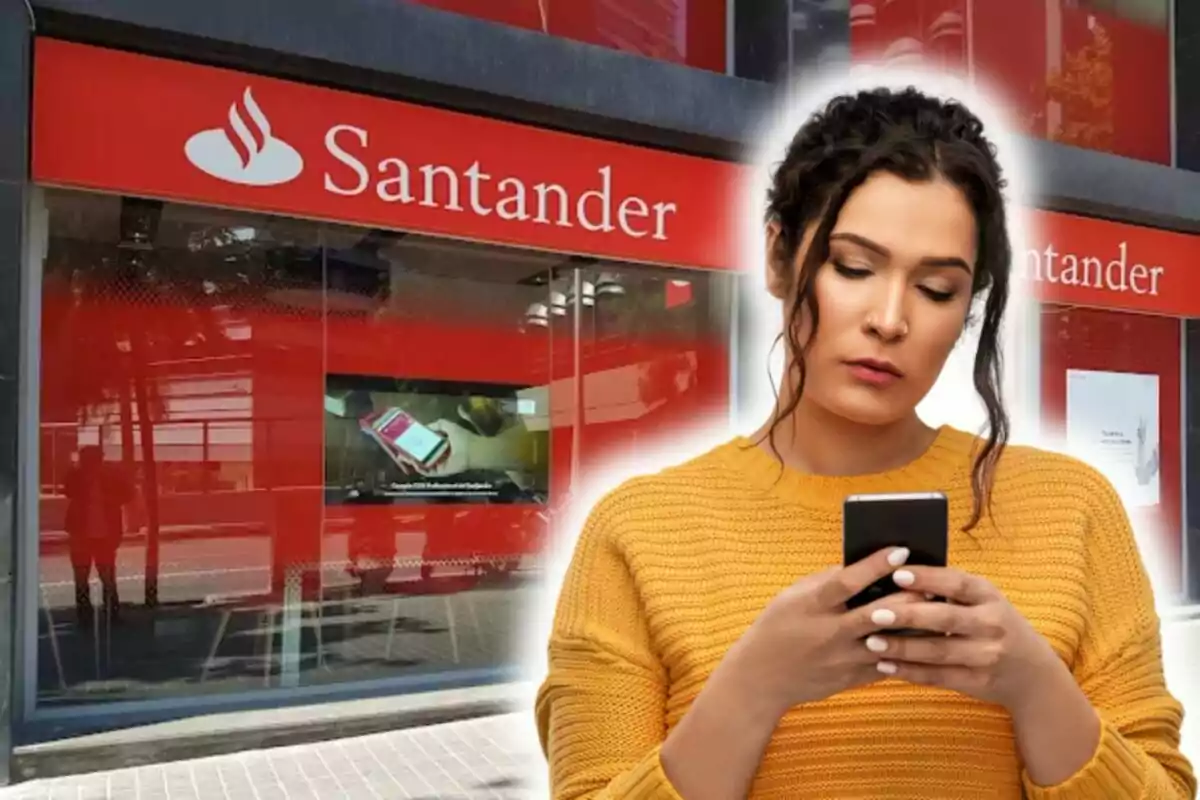 Mujer usando un teléfono móvil frente a una sucursal del banco Santander.