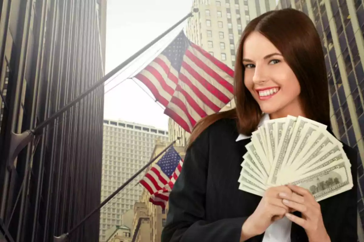 Mujer sonriente con traje sosteniendo billetes de dólar en una calle con banderas de Estados Unidos y edificios altos de fondo