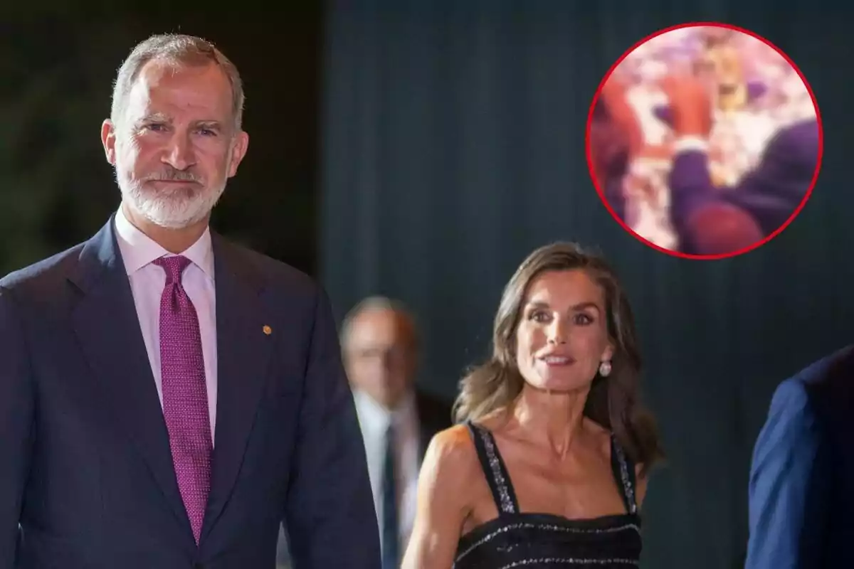 Felipe VI y Letizia elegantemente vestida camina en un evento nocturno con un fondo oscuro y un círculo rojo que destaca una imagen borrosa en la esquina superior derecha.