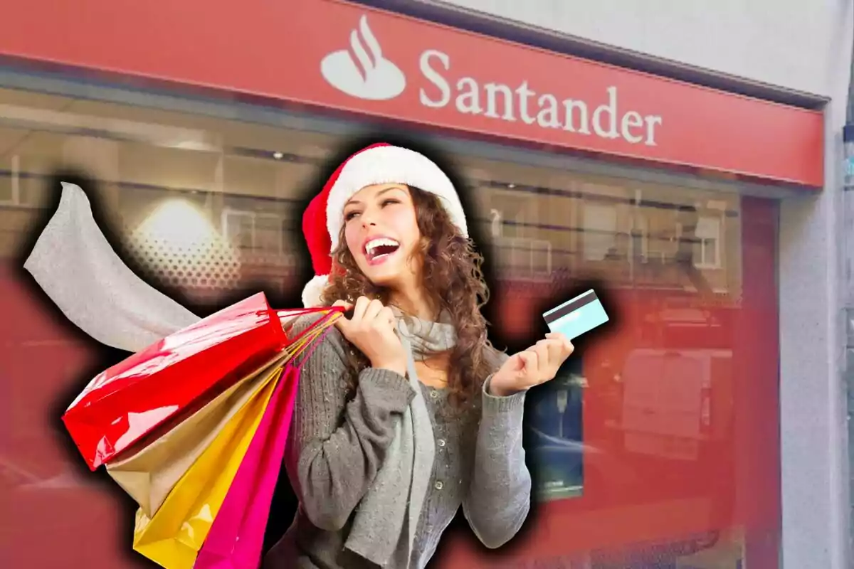 Mujer sonriente con gorro navideño sosteniendo bolsas de compras y una tarjeta de crédito frente a una sucursal del Banco Santander.