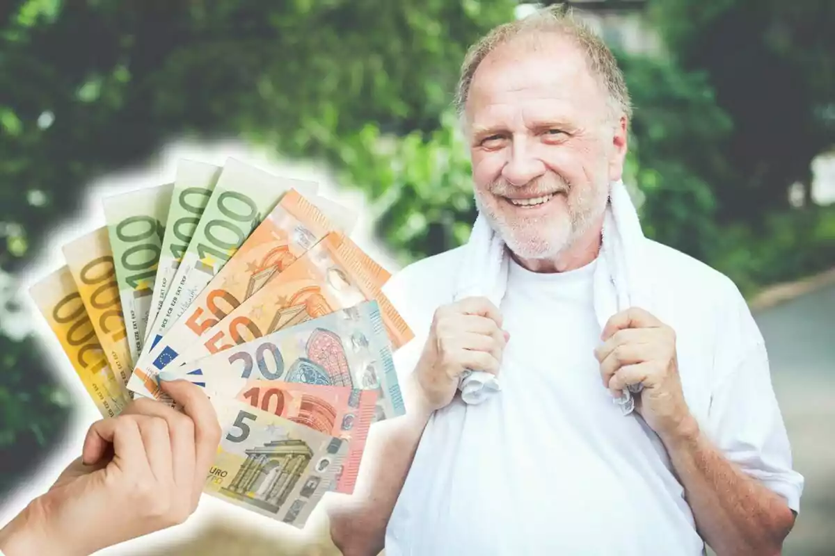 Hombre mayor sonriendo con una toalla alrededor del cuello y una mano sosteniendo billetes de euro.