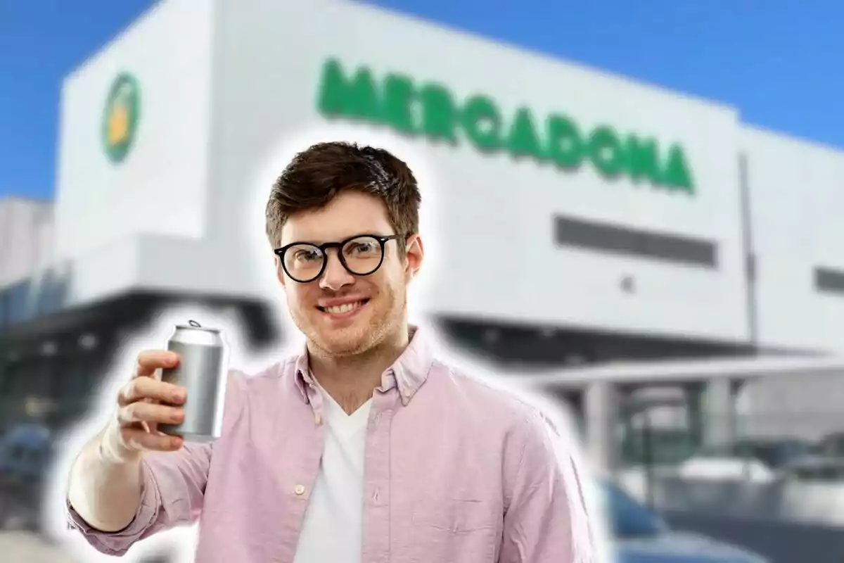 Un hombre con gafas sosteniendo una lata frente a un edificio con el logo de un supermercado Mercadona de fondo.