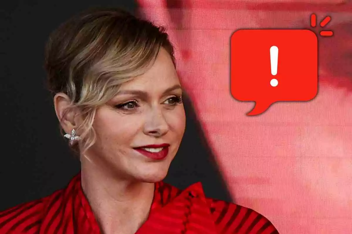Charlene de Mónaco con labios rojos y blusa roja mirando hacia la derecha con un ícono de advertencia en forma de globo de diálogo rojo a su lado