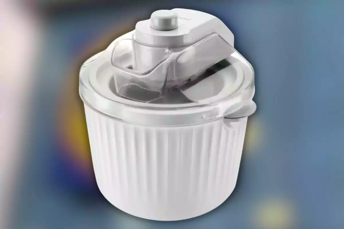 Máquina para hacer helados de color blanco con tapa transparente sobre un fondo desenfocado.