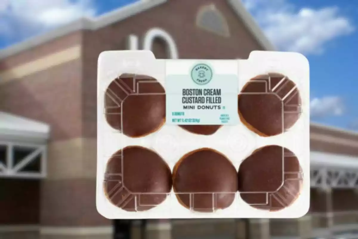 Paquete de mini donas rellenas de crema pastelera cubiertas de chocolate sostenido frente a una tienda Paquete de mini donas rellenas de crema pastelera cubiertas de chocolate sostenido frente a una tienda
