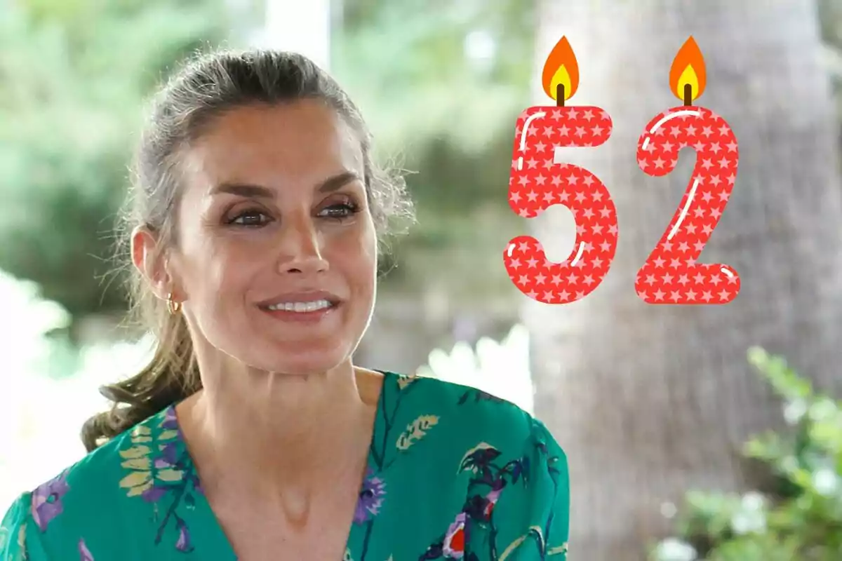 Letizia sonriente con una blusa verde estampada y el número 52 con velas encendidas al lado.