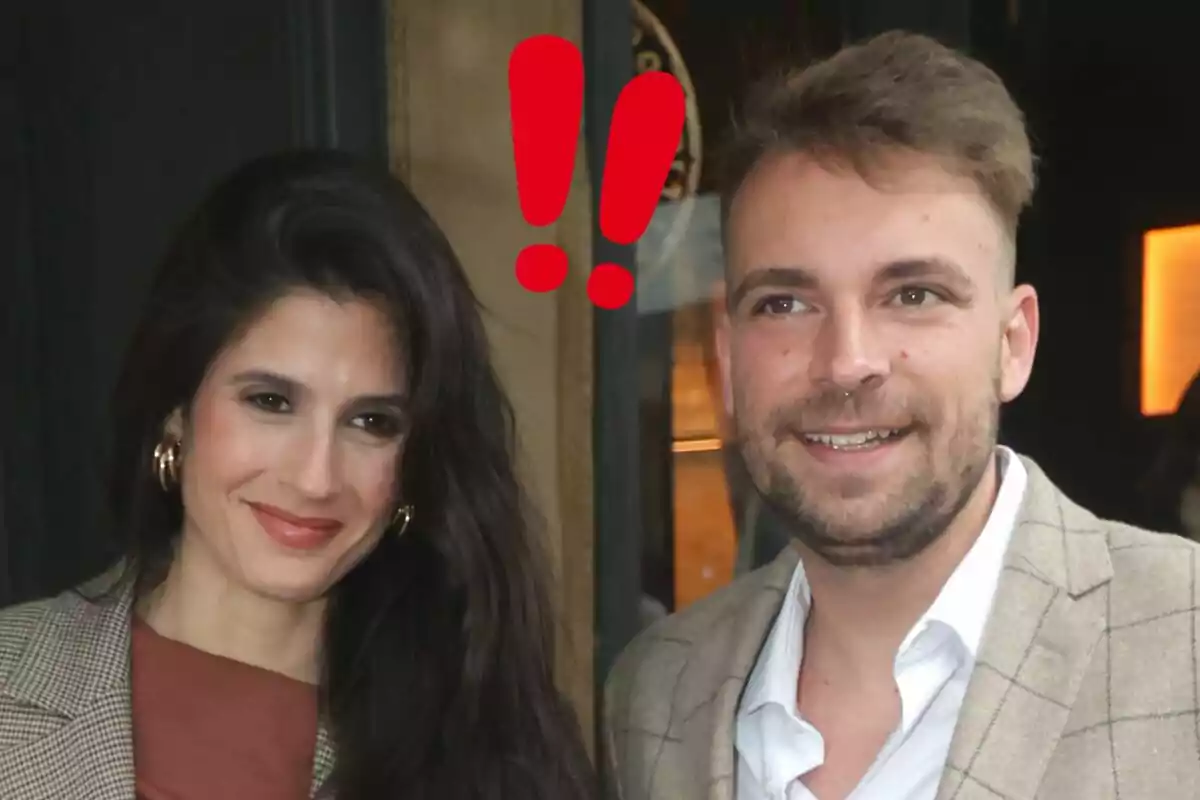 María Sánchez y José María Almoguera sonríen juntos mientras posan para una foto, ambos vestidos de manera elegante y con dos signos de exclamación rojos sobre sus cabezas.