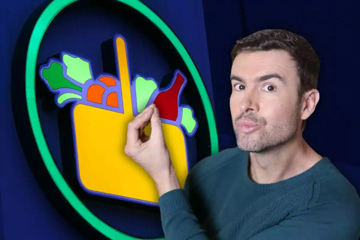 Hombre con suéter verde posando de manera divertida junto a un letrero colorido de supermercado con verduras y una botella