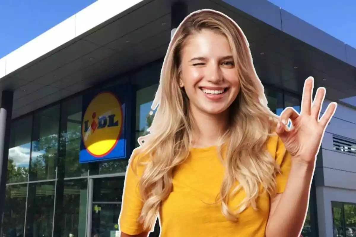 Una mujer sonriente con camiseta amarilla hace un gesto de "ok" frente a una tienda Lidl.