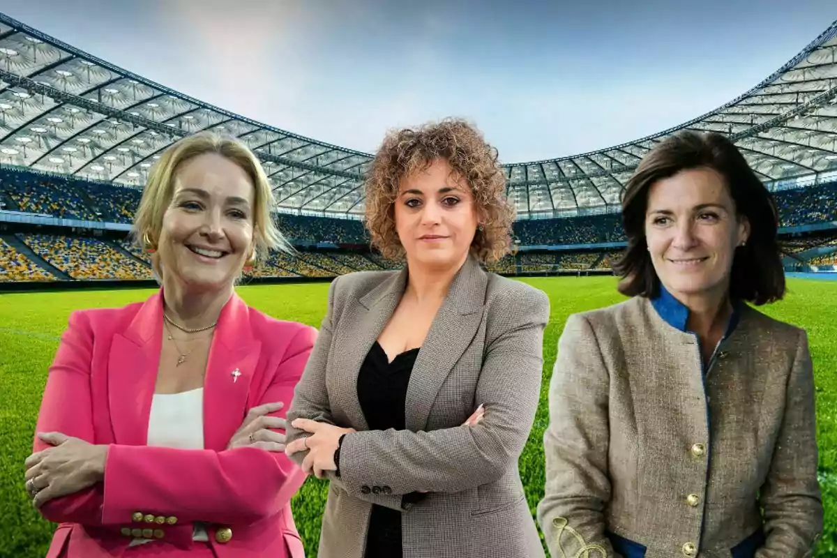 Tres mujeres posan en un estadio de fútbol, cada una con una chaqueta diferente, sobre el césped verde y con las gradas de fondo.