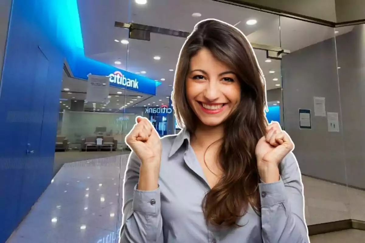 Mujer sonriente con camisa gris frente a la entrada de un banco. Mujer sonriente con camisa gris frente a la entrada de un banco.